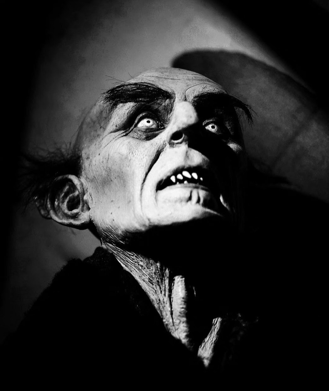 Figura teatral en blanco y negro con mirada elevada y sombras marcadas.